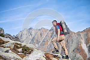 Zrelý muž s batohom na turistike v horách v lete.