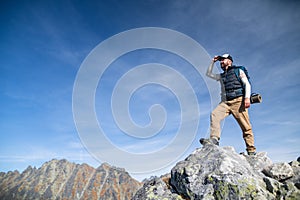 Mature man with backpack hiking in mountains in summer.