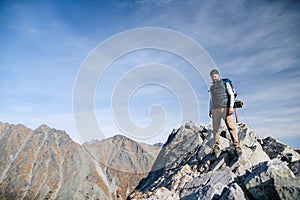 Mature man with backpack hiking in mountains in summer.