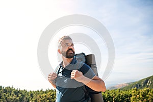 Mature man with backpack hiking in mountains in summer.