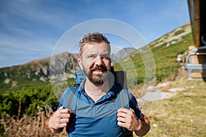 Mature man with backpack hiking in mountains in summer.