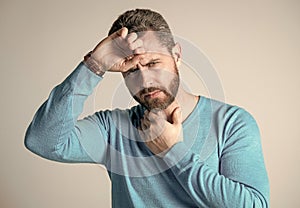 mature man with beard has heacache suffer from headahce on grey background, malaise