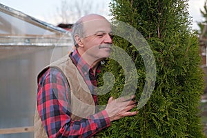 Mature man being proud of his garden hugging his favourite tree