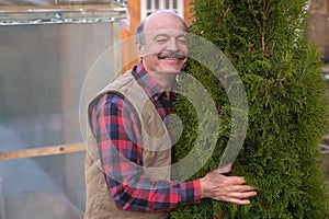 Mature man being proud of his garden hugging his favourite tree