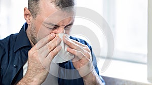 Mature Man Blowing Nose In Paper Tissue Sitting At Home