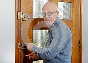 Mature man with blue pullover close the door
