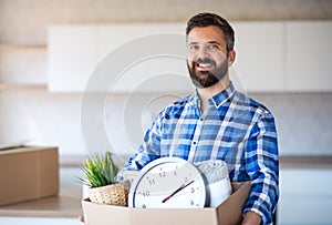 Mature man with box moving in new unfurnished house.