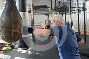 Mature man boxing punching bag.