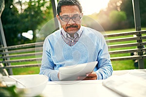 Mature, man and breakfast with tablet for social in backyard reading news in retirement. Male person, food and tech in