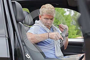 mature man in car fastening seatbelt