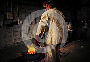 Mature man checks heat of crucible for hot metal bronze pour