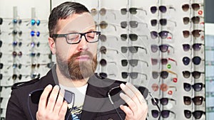 Mature man choosing between two pairs of sunglasses at the store