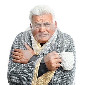 Mature man with cup of hot beverage suffering from cold on background