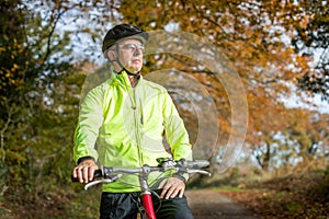 Mature Man Cycling Along Autumn Country Road