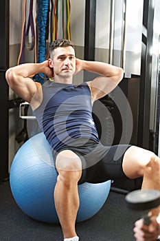 mature man doing abdominal crunches at the gym on a pilates ball