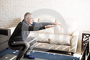 Mature man doing squats workout at home