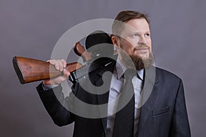 Mature man dressed in suit with tommy gun