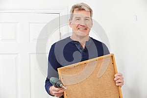 Mature Man Drilling Wall To Hang Picture Frame