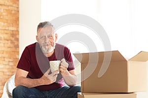 Mature man with drinking tea after moving to new house