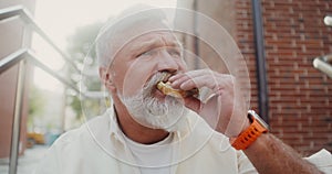 Mature man eats sandwich outdoors