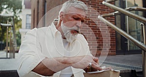 Mature man eats sandwich outdoors