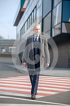 Mature man in elegant coat crossing the street