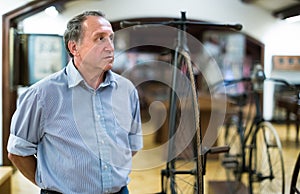 Mature man examines the exhibit in museum