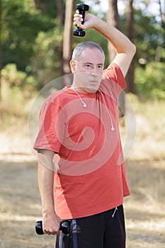 Mature man exercising with dumbbell at park