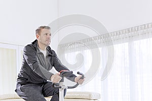 Mature man exercising on a spin bike at home