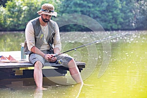 Mature man fishing in Lake while sitting on pier