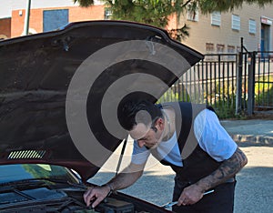 mature man fixing a breakdown in his car engine with tools