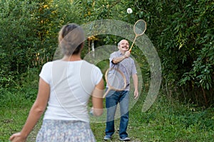Mature man and girl playing badminton outdoors.