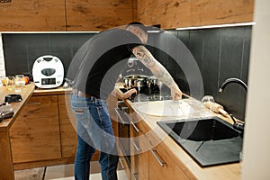 Mature man in glasses with tattoo sleeve on arm learning to bake, handmade pies, bread at modern technological kitchen