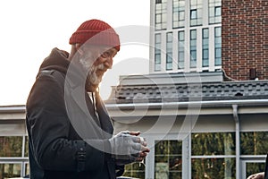 Mature man with grey beard asking for some money by citizens of city