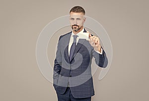 mature man with grizzled hair in suit showing credit or debit card copy space, contact us