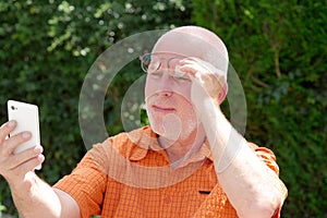 mature man has problems with his eyesight for reading on his smart phone