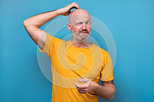 Mature man having doubts and with confuse face expression while scratching head