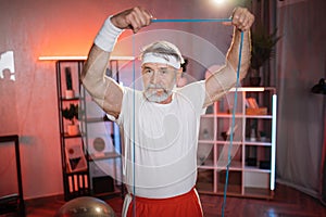 Mature man having evening workout with resistance band