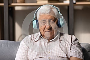 Mature man in headphones listens music with eyes closed