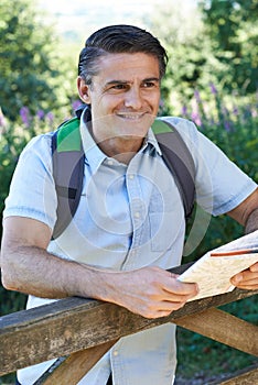 Mature Man Hiking In Countryside Looking At Map