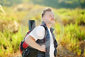 Mature man hiking on sunny summer day. Adventure concept. Solo travel. Hitch-hiking. Backpacking trip