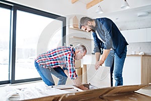 A mature man with his senior father assembling furniture, a new home concept.