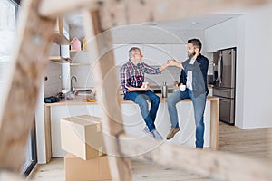 A mature man with his senior father furnishing new house, a new home concept.