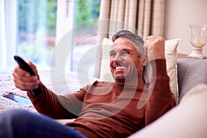 Mature Man At Home Relaxing On Sofa Watching Sports On TV