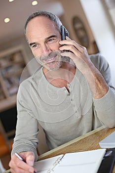 Mature man at home talking on smartphone