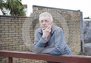 Mature man leaning against a wooden gate outdoors