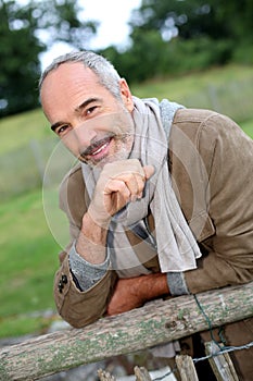 Mature man leaning on wood fence