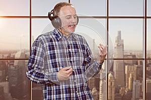 Mature man listening to music in headphones and enjoying.