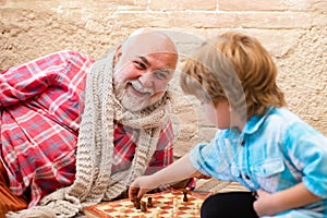 Mature man with little boy playing chess. Chess competition. Senior man thinking about his next move in a game of chess