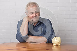 Mature man looking at a piggy bank